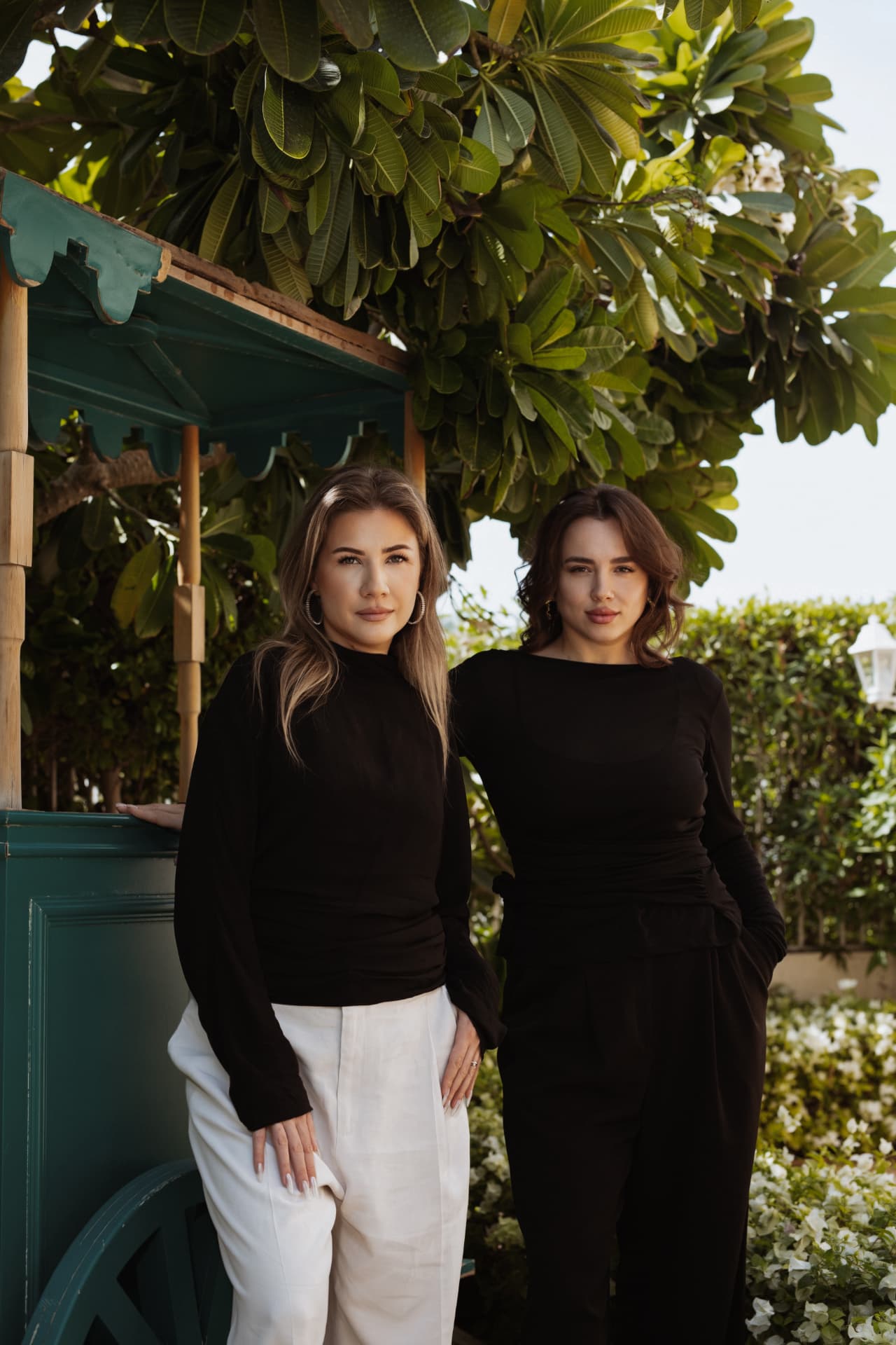 The two TRIÉ founders standing in the green salon garden